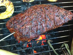 a steak is cooking on the grill with other food items around it, including bananas and pineapples