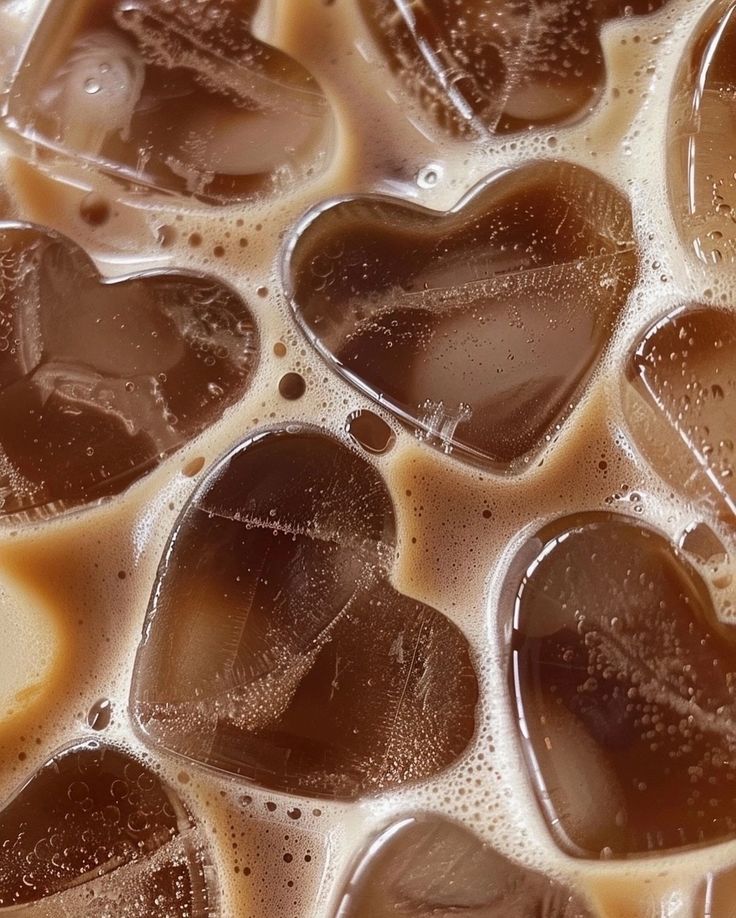 heart shaped ice cubes are shown in the liquid on top of eachother