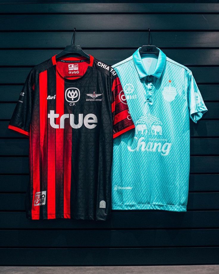 two soccer jerseys hanging on a wall next to each other in front of a black garage door