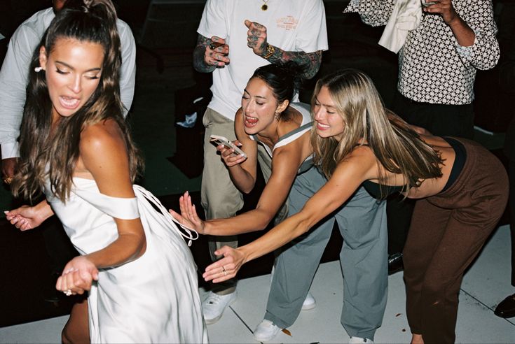 several young women are dancing on the dance floor at a party with other people around them