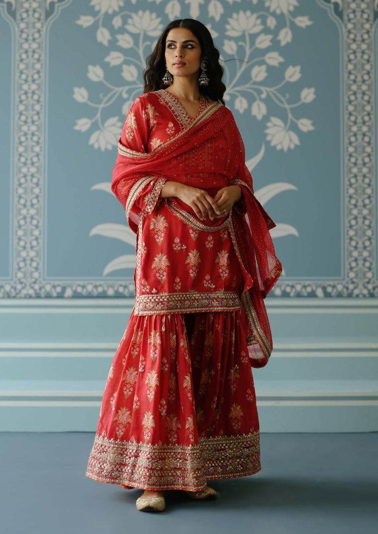 This pretty ensemble in our floral jaal, with an intricate border embroidery. The short tunic with matching dupatta embroidered in sequins and gold thread, and voluminous sharara adds a feminine grace. Designer Red Sharara In Chinon, Straight Kurta Sharara With Resham Embroidery For Navratri, Navratri Straight Kurta Sharara With Resham Embroidery, Navratri Resham Embroidery Sharara With Straight Kurta, Red Palazzo Set With Intricate Embroidery, Red Palazzo Set With Intricate Embroidery And Traditional Drape, Red Chikankari Embroidery Sharara For Designer Wear, Red Diwali Sharara With Resham Embroidery, Diwali Red Sharara With Resham Embroidery