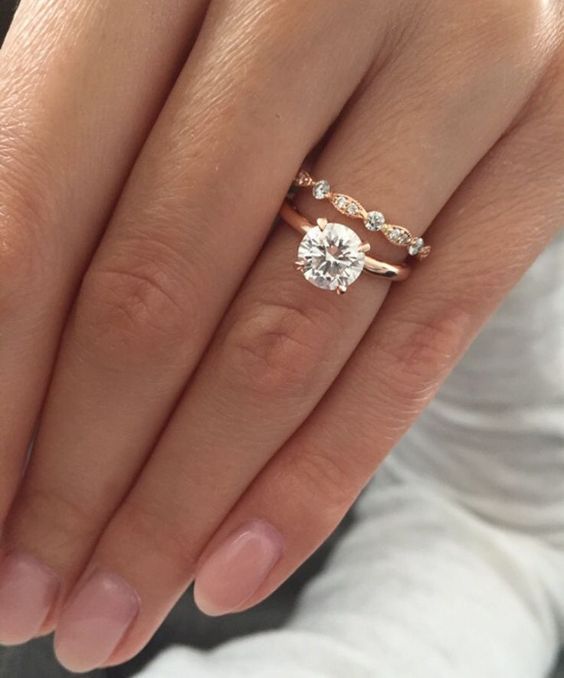 a woman's hand with two engagement rings on it and the other hand holding an engagement