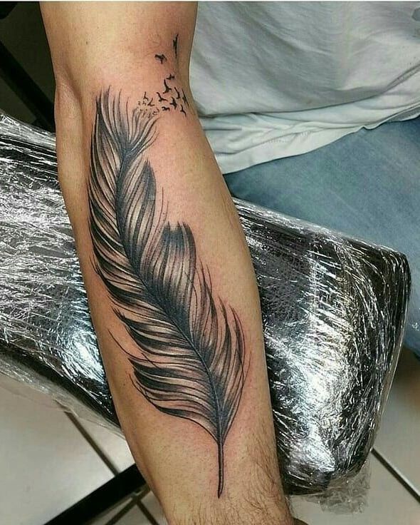 a black feather tattoo on the leg