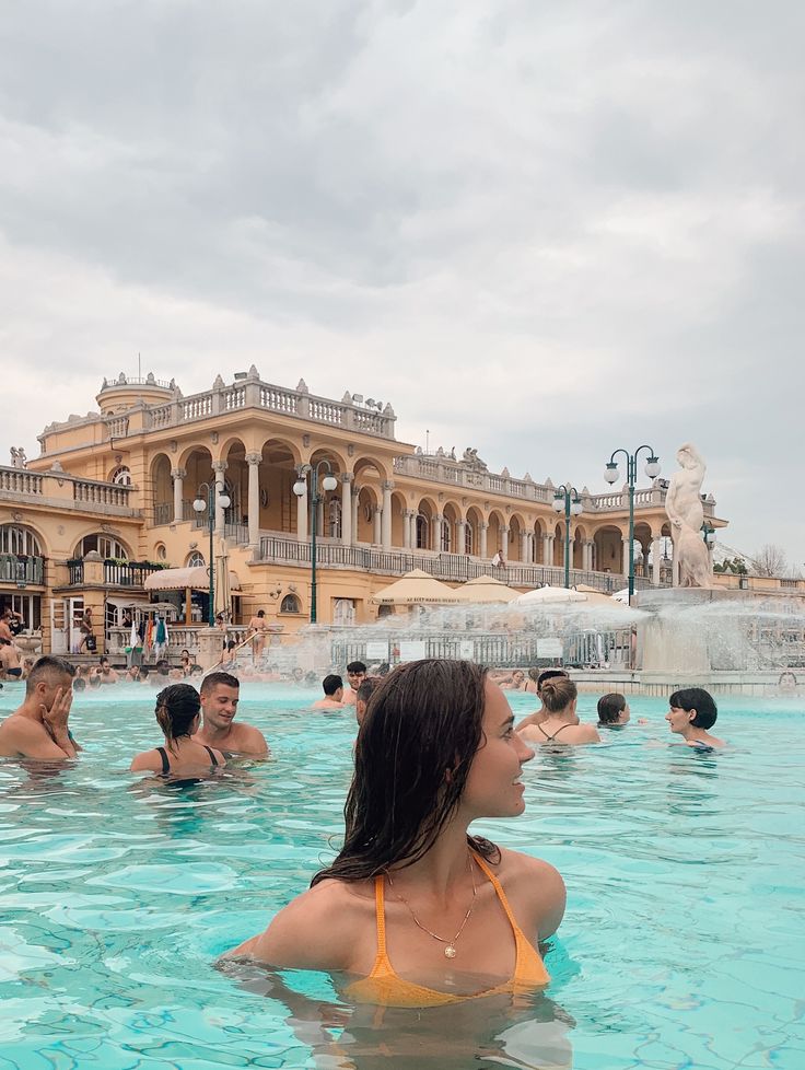 several people are in the pool and one is wearing a yellow bathing suit while others swim nearby