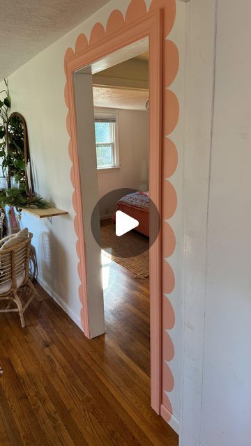 an open door in a room with wooden floors and walls painted pink, white and orange