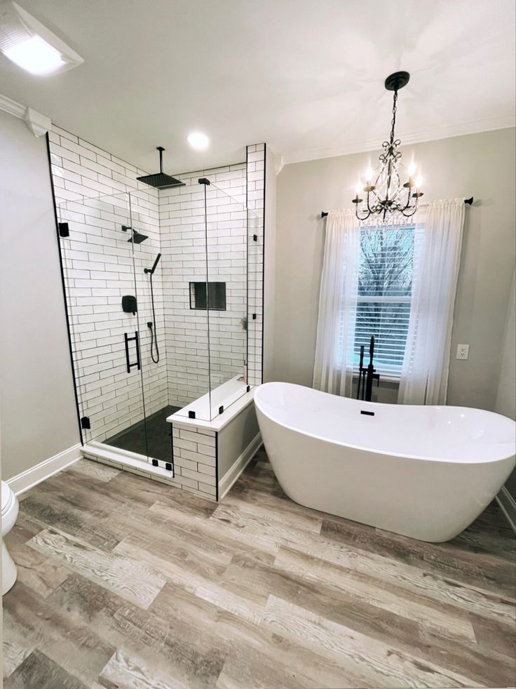 a white bathtub sitting next to a toilet in a bathroom under a chandelier