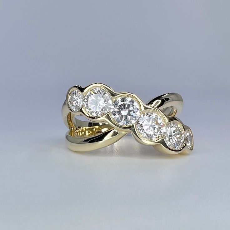 two gold wedding rings with three diamonds on each one, set against a gray background