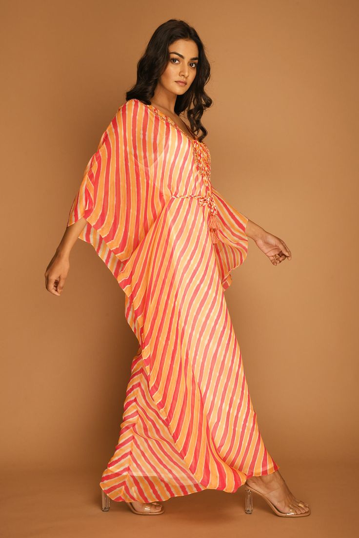 Carrot kaftan tunic with all-over Leheriya print, embroidered V-neckline and asymmetric hem. Comes with braided tie-up belt.
Component: 2
Printed, Embroidered
Neckline: V-Neck
Sleeve Length: Three Quarter
Fabric: Georgette
Color: Orange
Asymmetric hem
Braided belt with tassels - Aza Fashions Festive Bollywood V-neck Maxi Dress, Summer Festive V-neck Kaftan, Festive V-neck Kurta For Vacation, Designer V-neck Summer Dresses, Summer Designer V-neck Dresses, Designer Summer V-neck Dress, Bollywood Style Festive V-neck Maxi Dress, Bollywood Style V-neck Festive Maxi Dress, Festive Bollywood Maxi Dress With V-neck