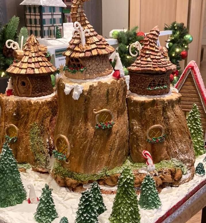 a table topped with lots of cakes covered in icing next to christmas trees and decorations