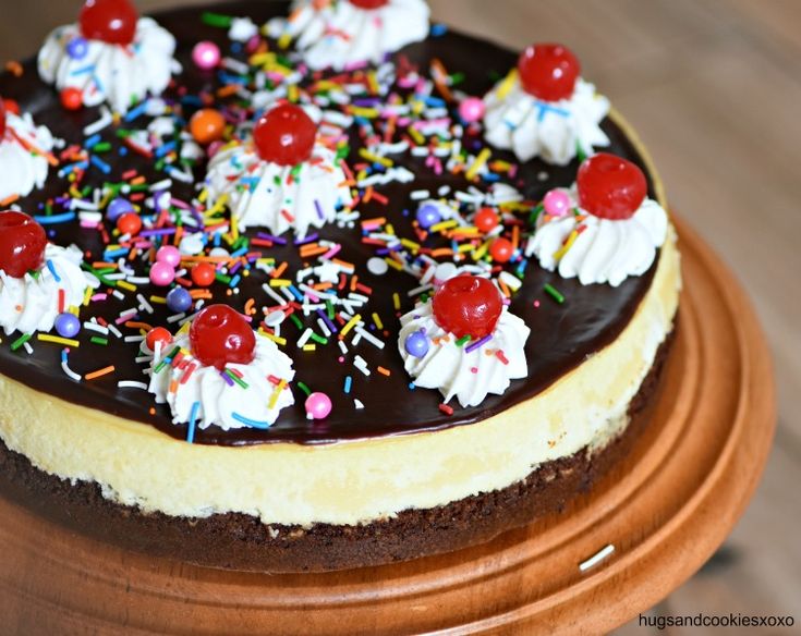 a chocolate cake with white frosting and sprinkles, topped with cherries