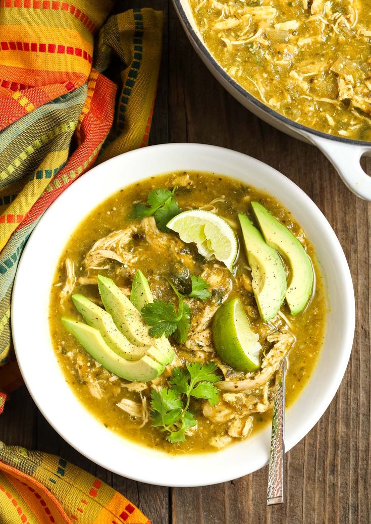 a bowl of chicken tortilla soup with avocado and cilantro