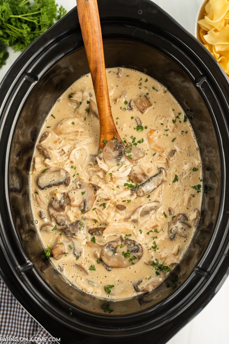 a crock pot filled with mushrooms and pasta