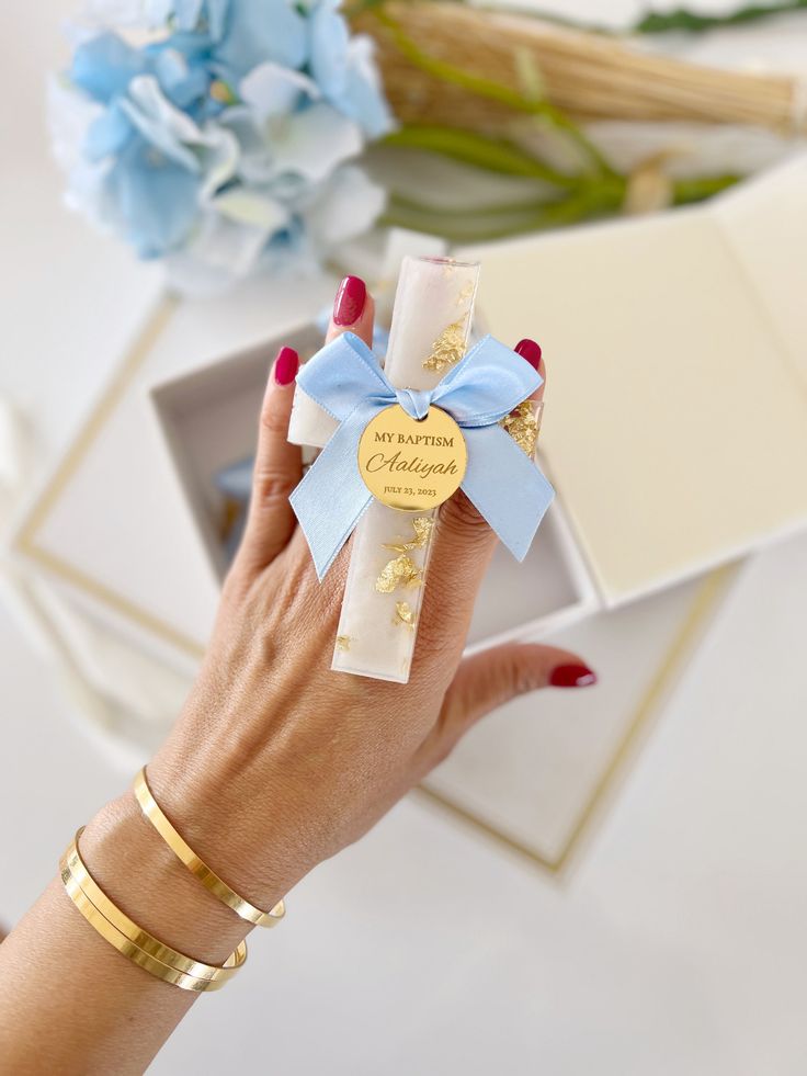 a woman's hand holding a small gift box with a blue bow on it