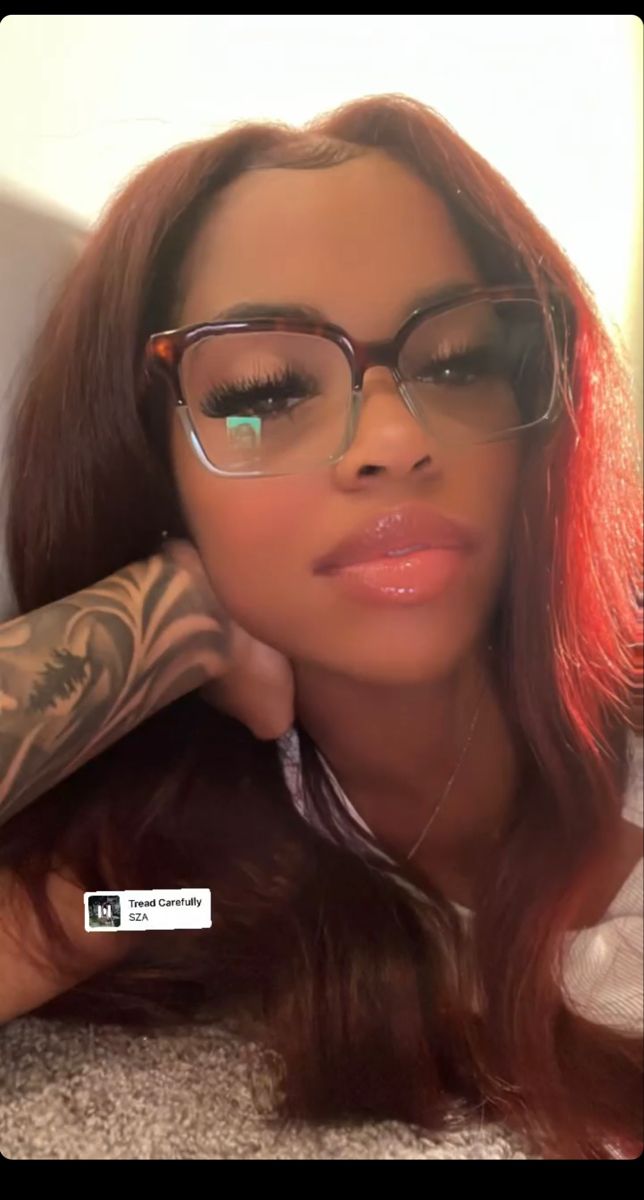 a woman wearing glasses with tattoos on her arm