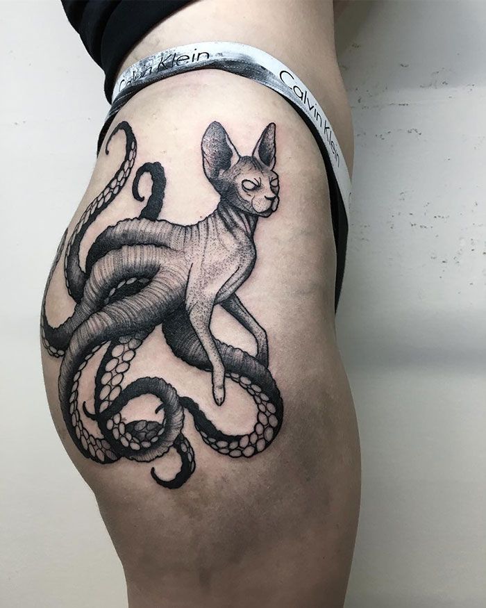 a woman's thigh with an octopus and cat tattoo on the side of her leg