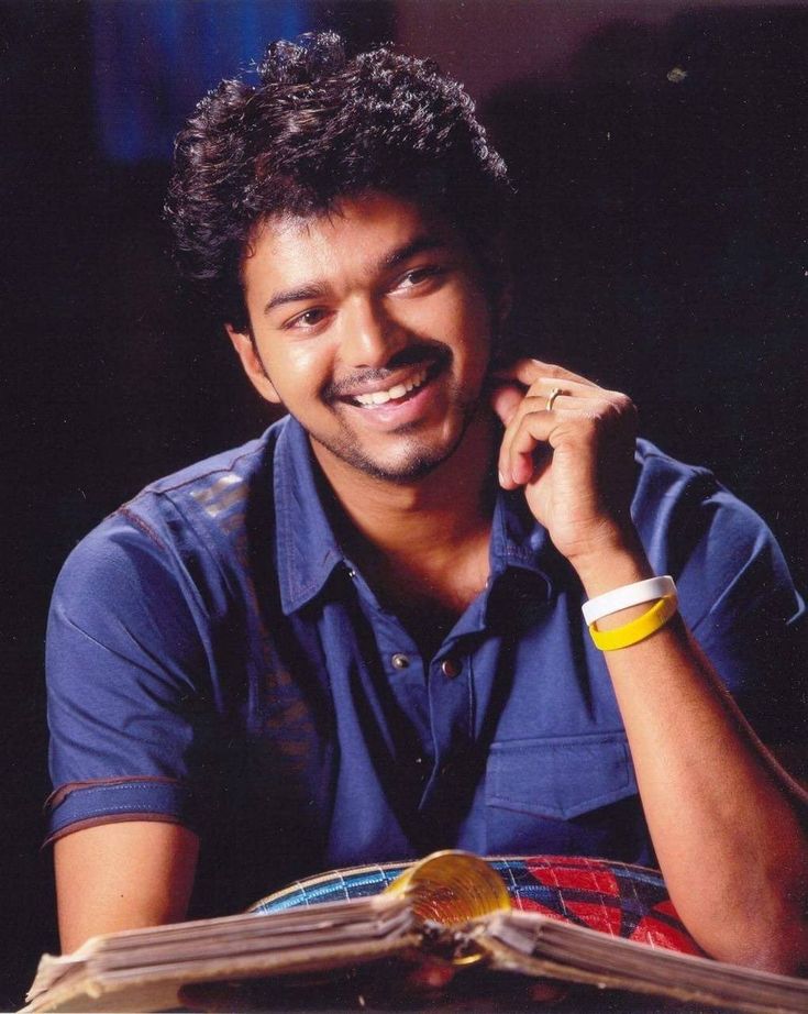 a man sitting at a table with an open book in front of him and smiling