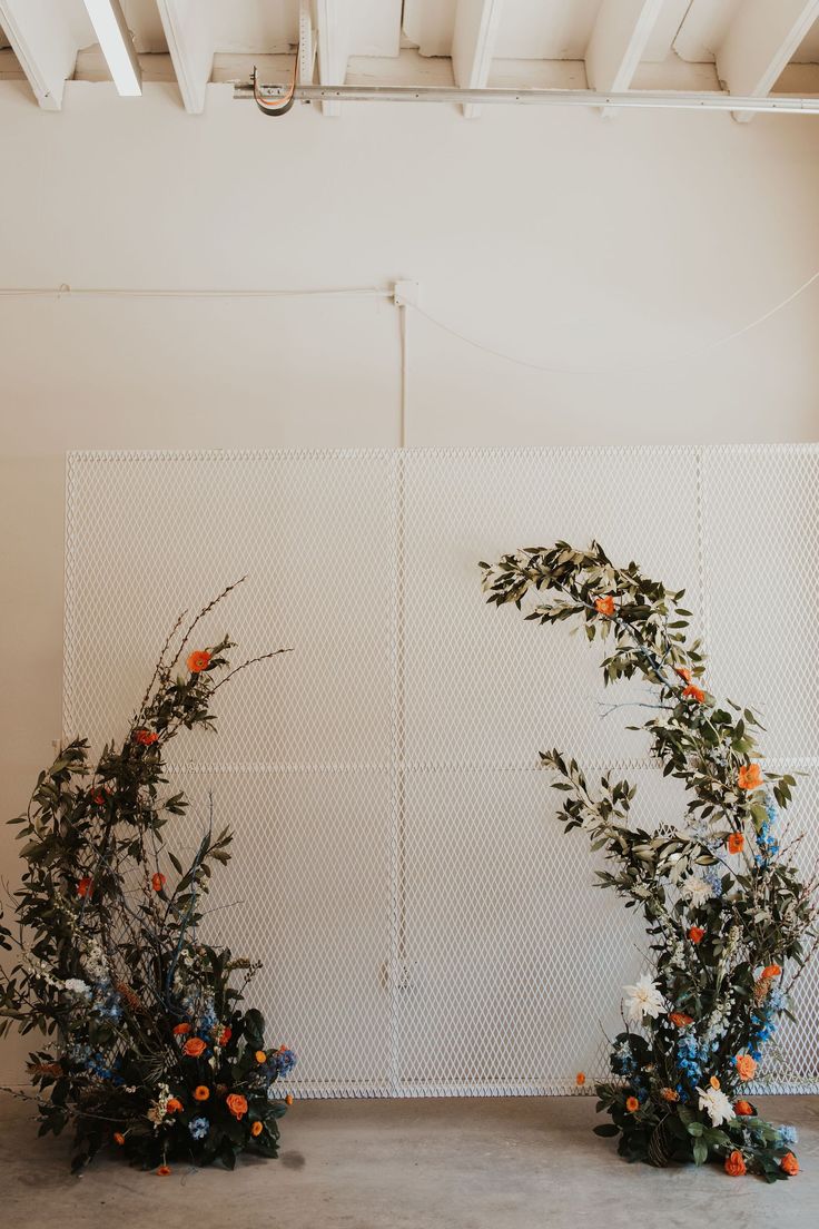 two floral arrangements are arranged on the floor in front of a white wall and ceiling