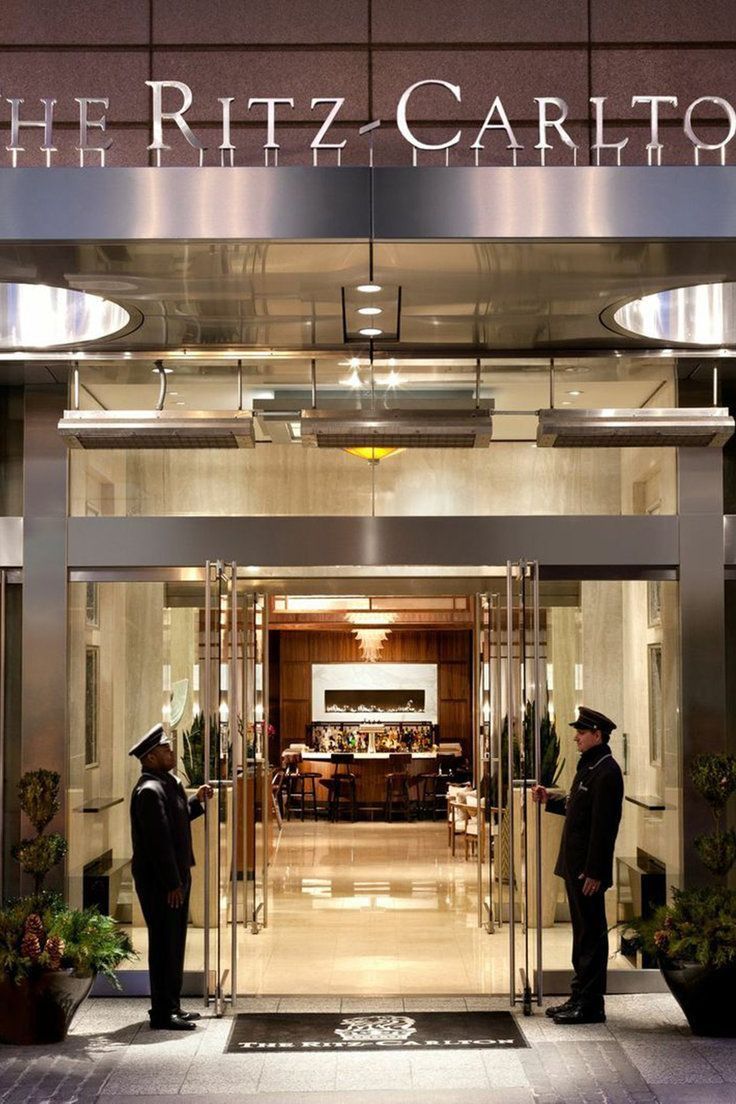 two men in suits are standing outside the ritz - carlton hotel, where it is located