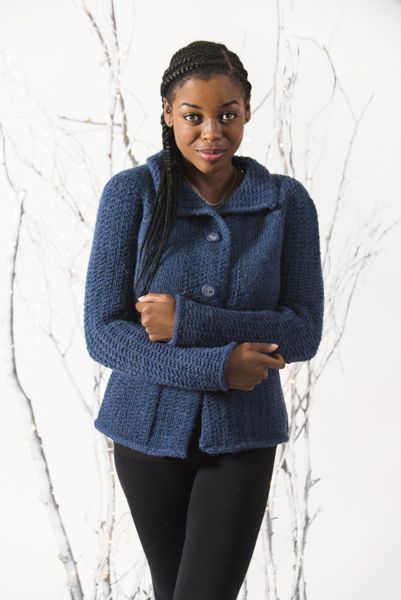 a woman standing in front of a tree wearing a blue jacket and black leggings