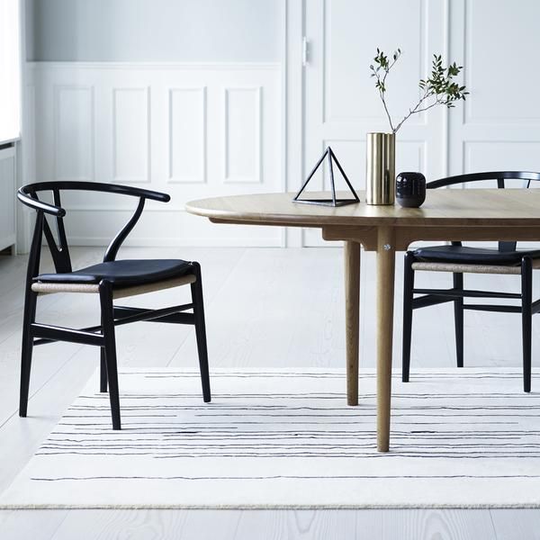 two chairs sitting at a table with a vase on top of it and a plant in the middle