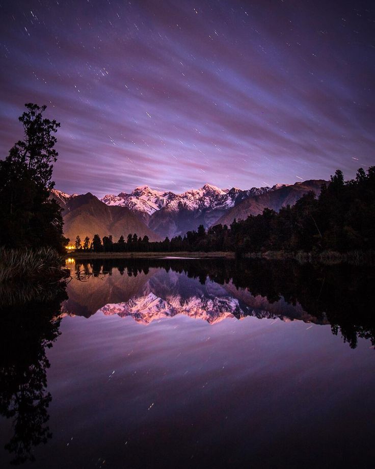 the night sky is reflected in water with mountains in the background