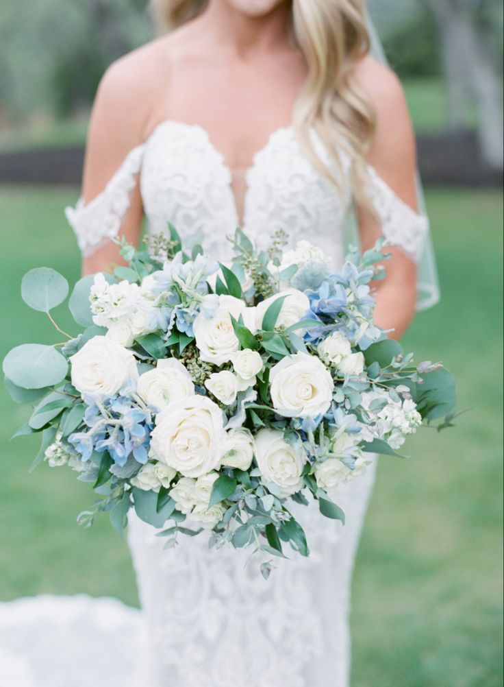 a bride holding a bouquet of white and blue flowers