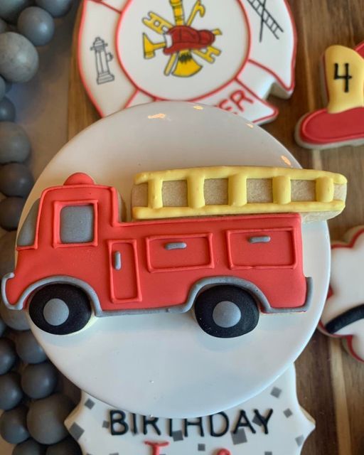 a birthday cake decorated like a firetruck on top of a table with other cookies