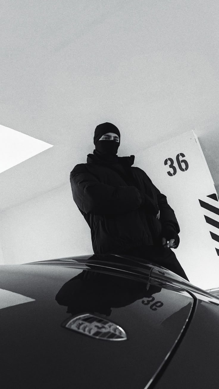 a man standing on the hood of a car in front of a gas station sign