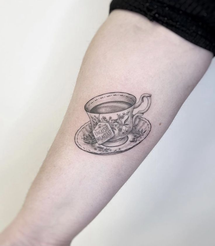 a small cup and saucer tattoo on the arm