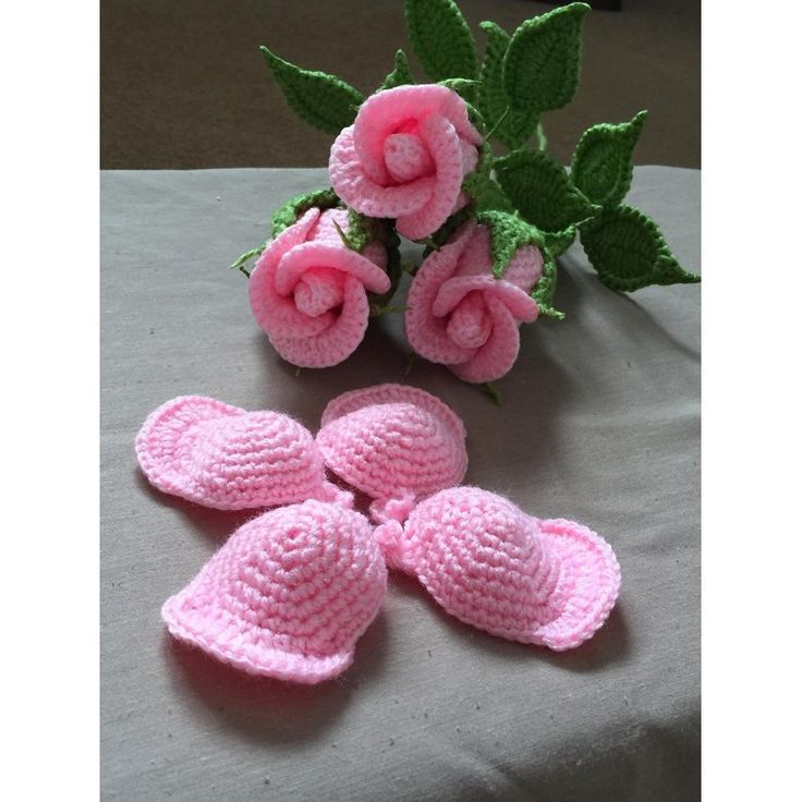 pink crocheted baby booties and flowers on a table