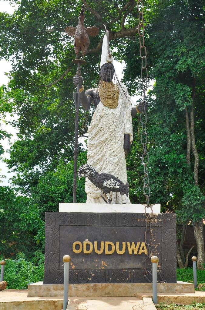 the statue is in front of trees and has a chain hanging from it's neck