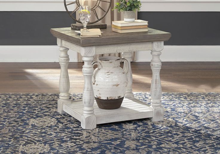 a white vase sitting on top of a wooden table next to a lamp and books