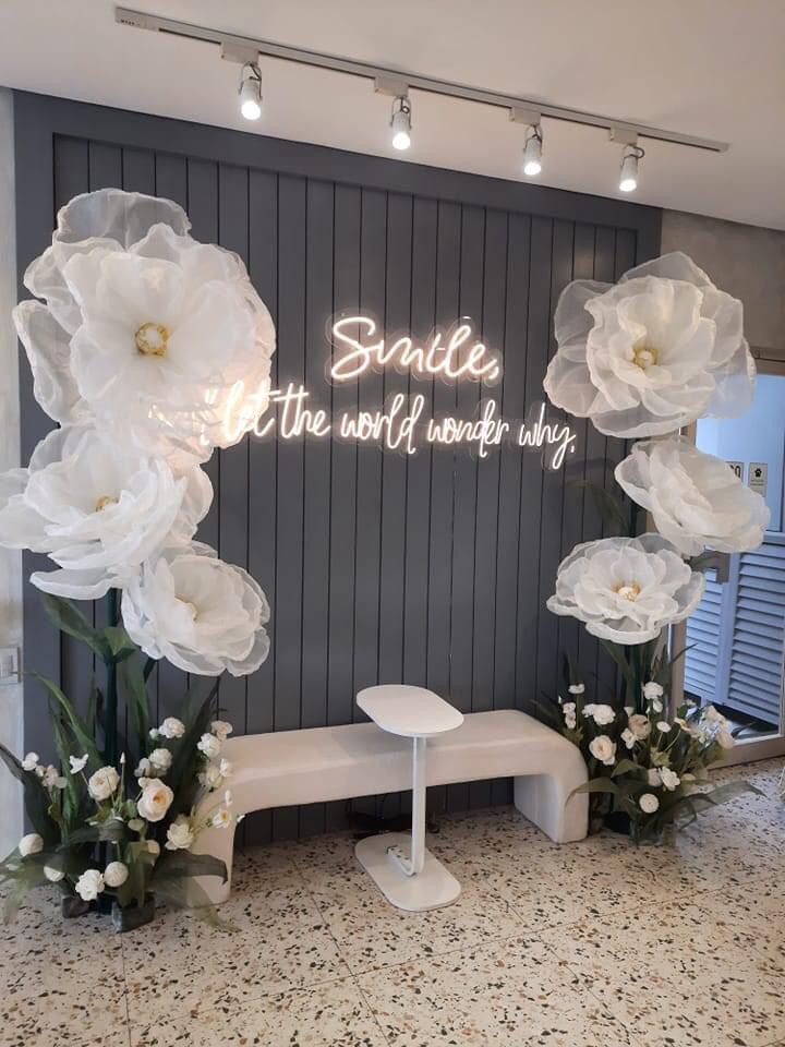 a white bench sitting in front of a wall with flowers on it