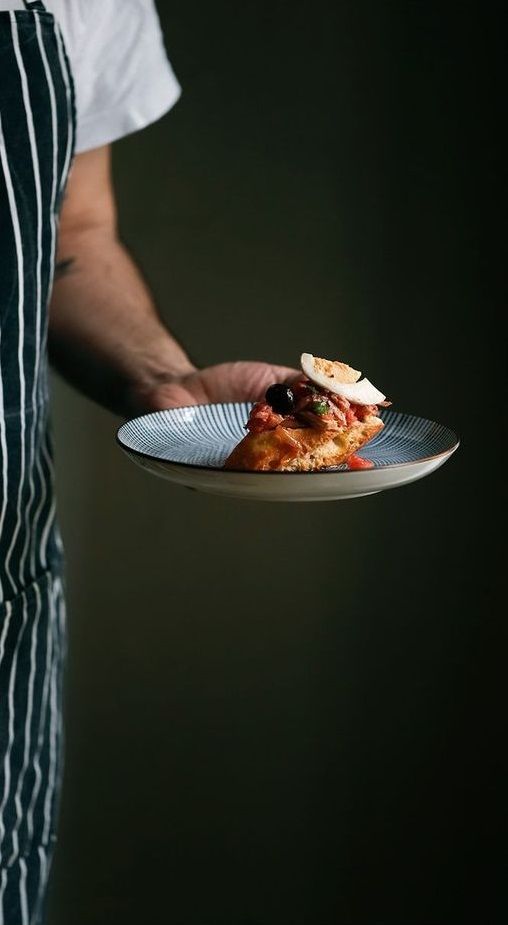 a person holding a plate with food on it in their hand and wearing an apron