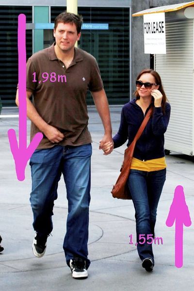 a man and woman walking down the street holding hands, with measurements for each other