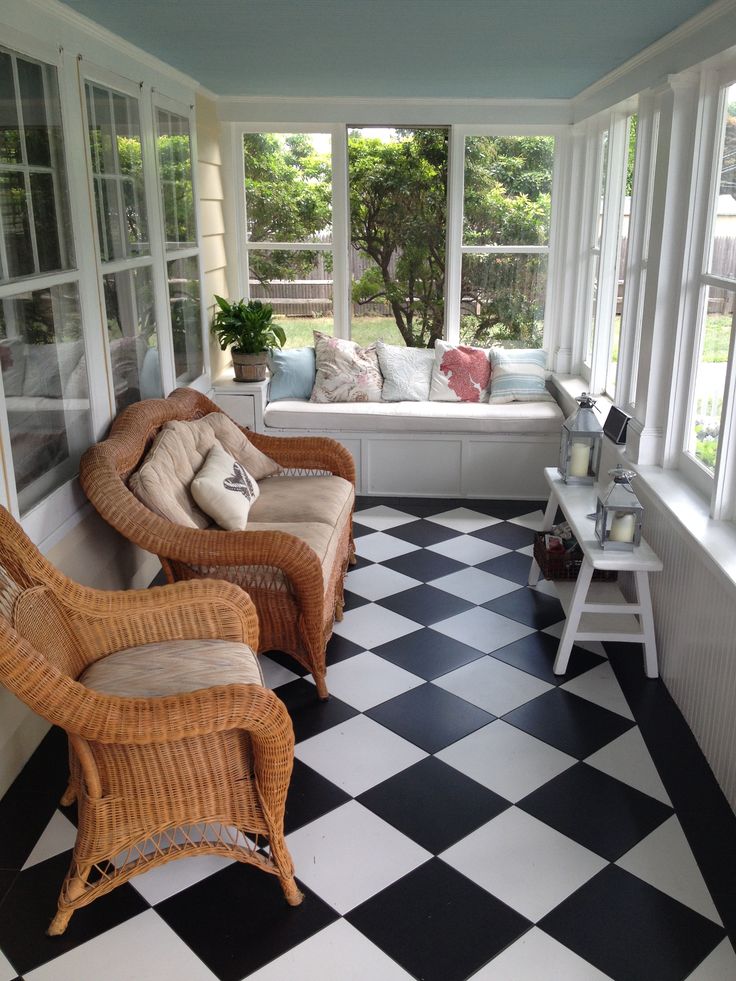 two wicker chairs sitting in front of windows on a black and white checkered floor