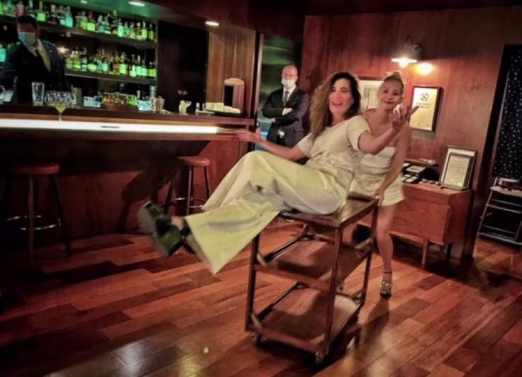 two women sitting at a bar posing for the camera