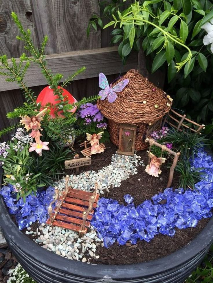 a potted planter filled with lots of flowers and miniature fairy houses on top of it