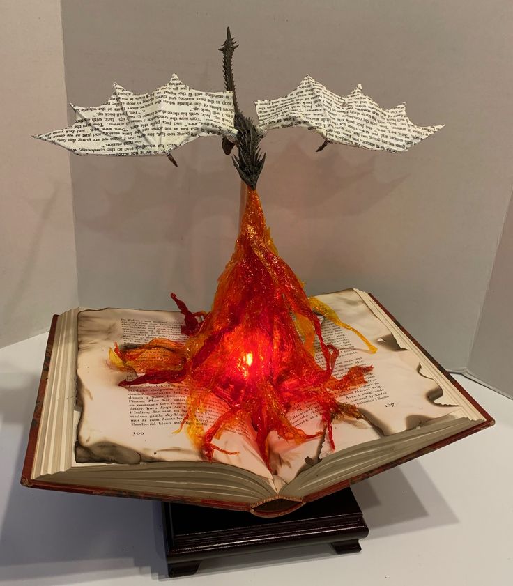 an open book with a sculpture on top of it that is shaped like a tree