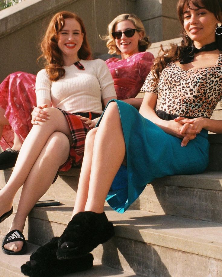 three women are sitting on the steps and one is wearing high heeled shoes with her legs crossed