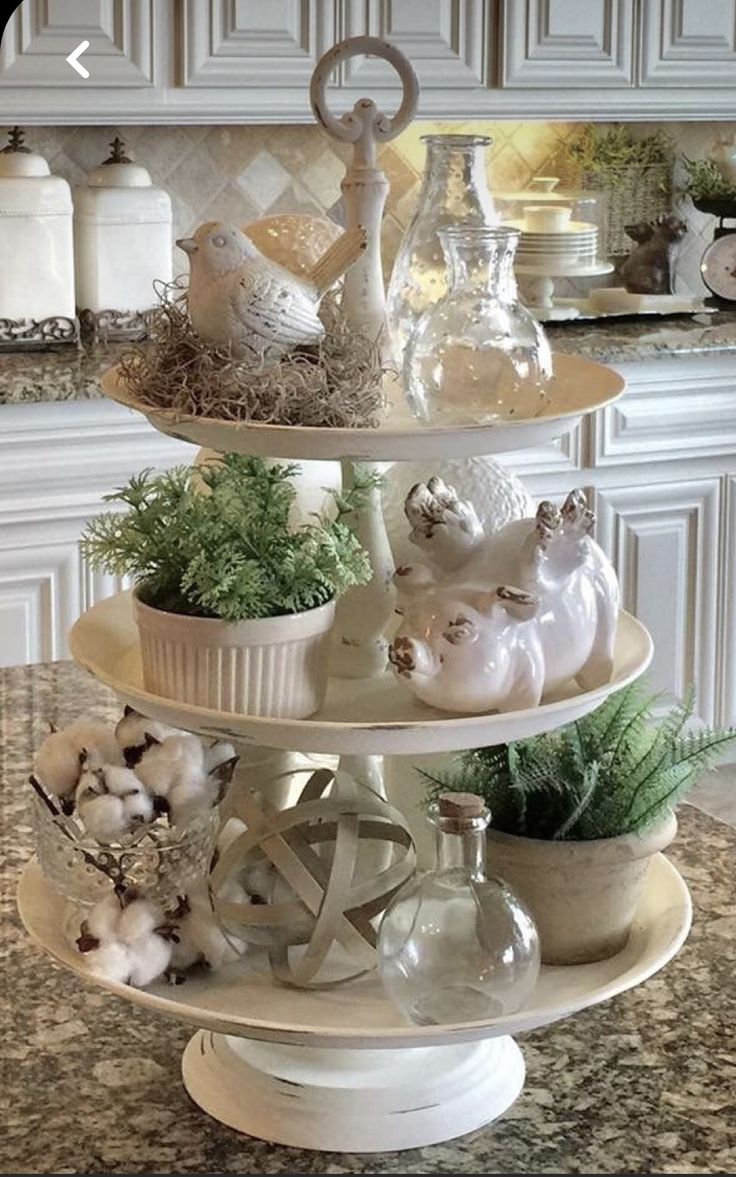 three tiered trays filled with glass vases and other items on top of a kitchen counter