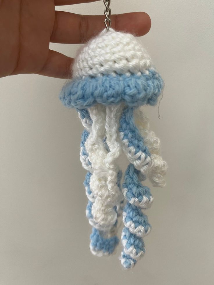 a crocheted jellyfish keychain is being held by a person's hand