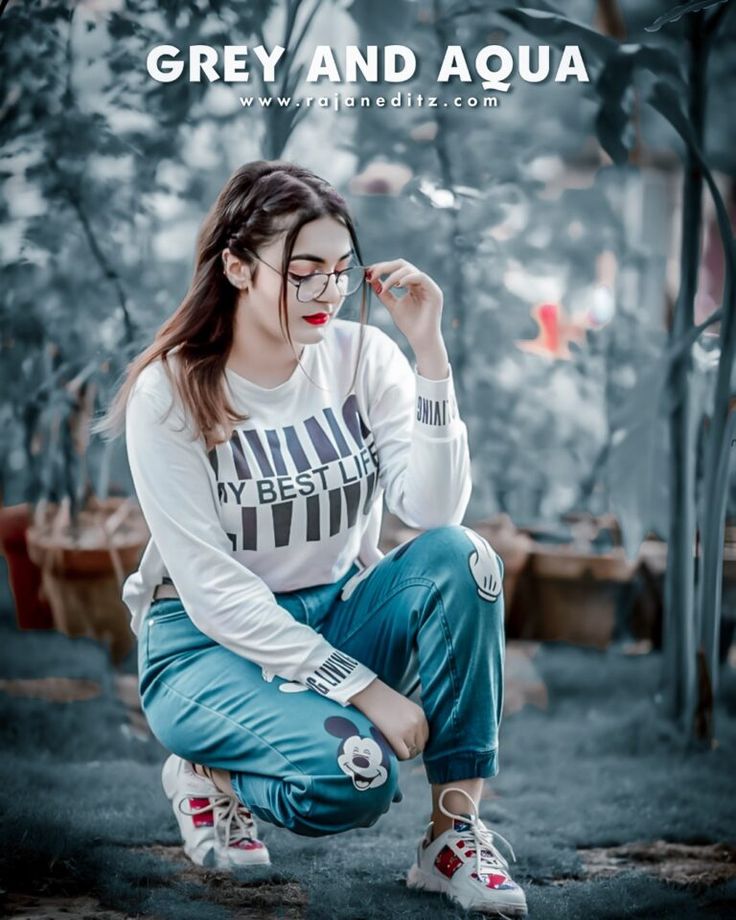 a young woman sitting on the ground with her hand in her mouth and wearing glasses