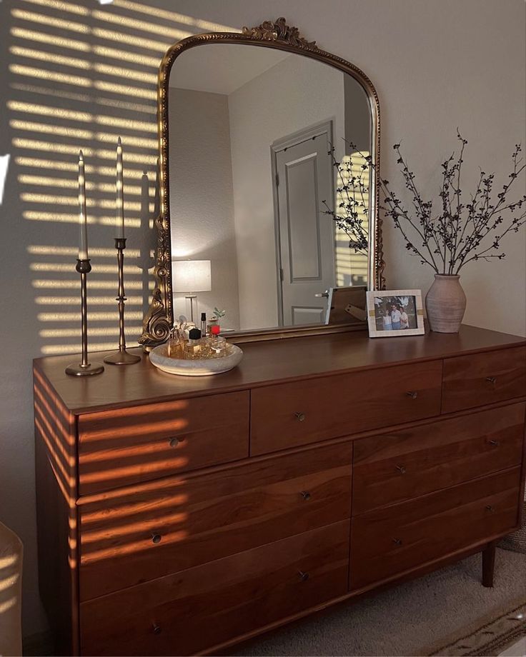 a dresser with a mirror and vase on it