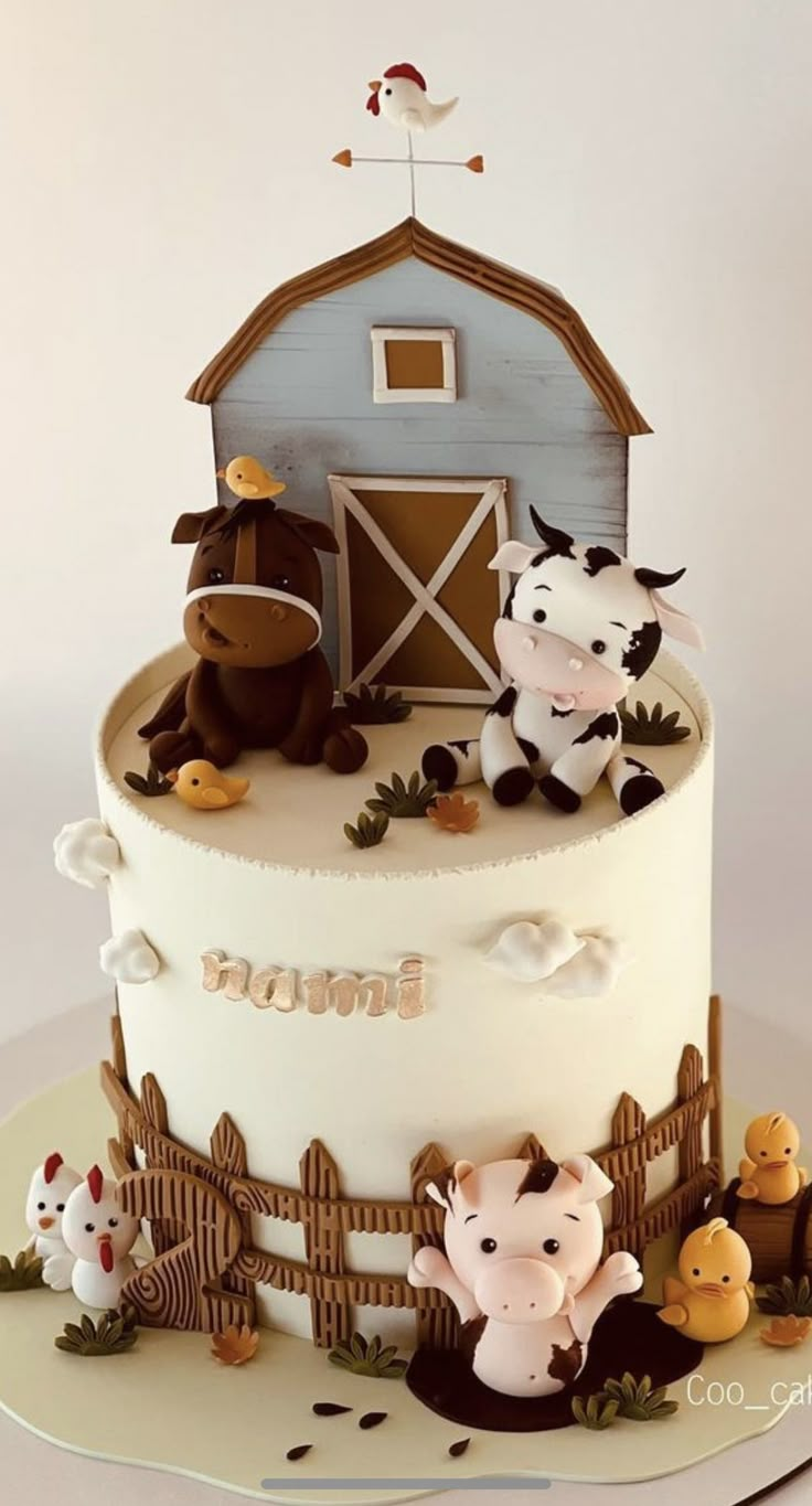 a three tiered cake with farm animals on the top and barn in the background