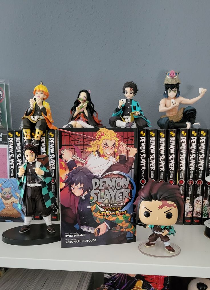 some anime figurines are sitting on a shelf next to books and dvds in front of a gray wall