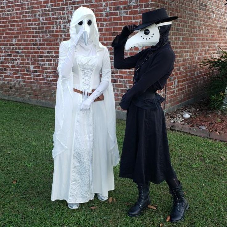 two people dressed up as ghost and skeleton standing in front of a brick building with grass