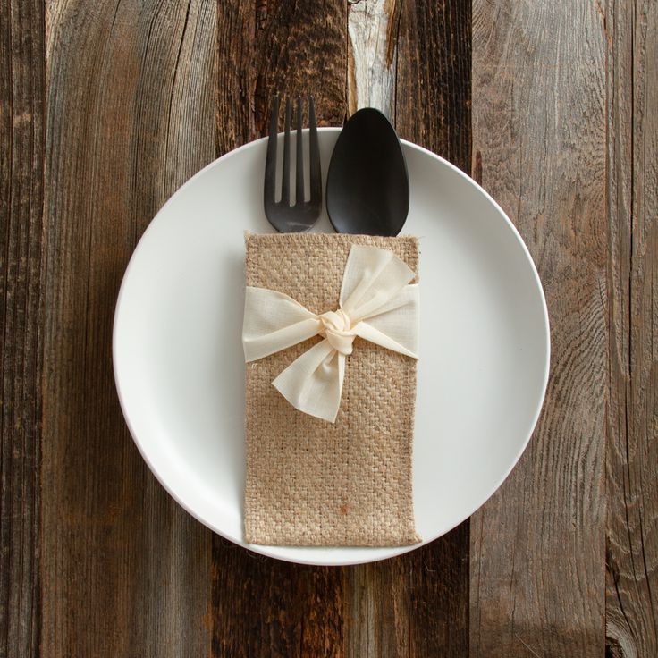 a white plate topped with a napkin and two black utensils next to a fork