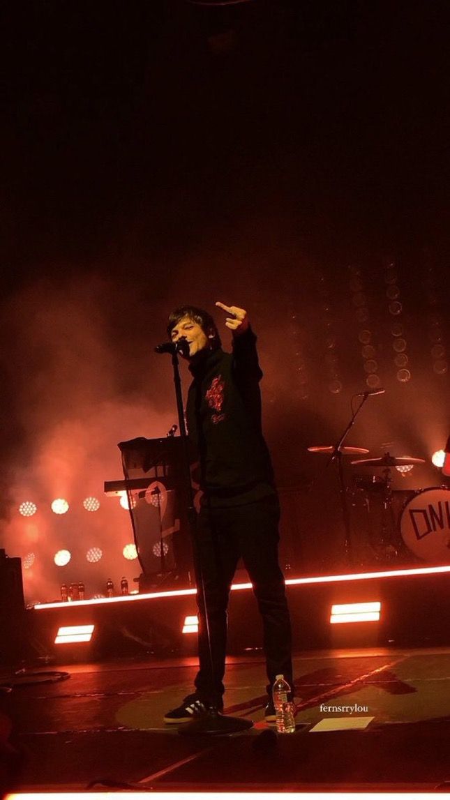 a man standing on top of a stage holding a microphone in front of his face