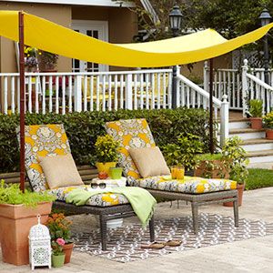 an outdoor seating area with yellow canopy and potted plants